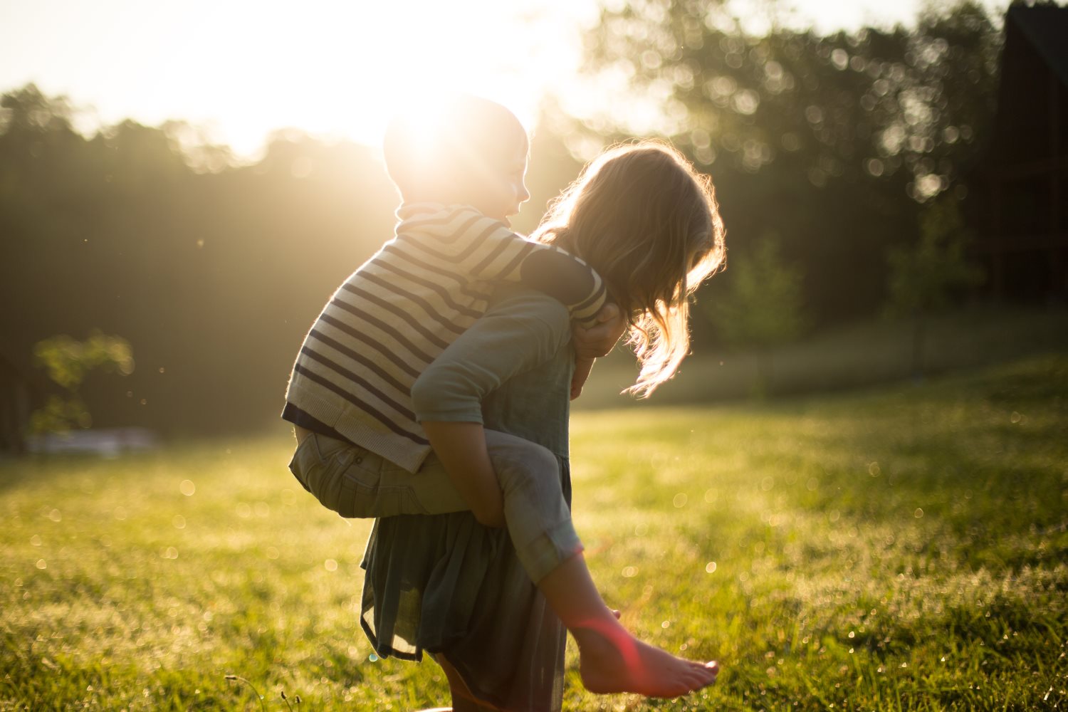 Older child carrying younger child on back